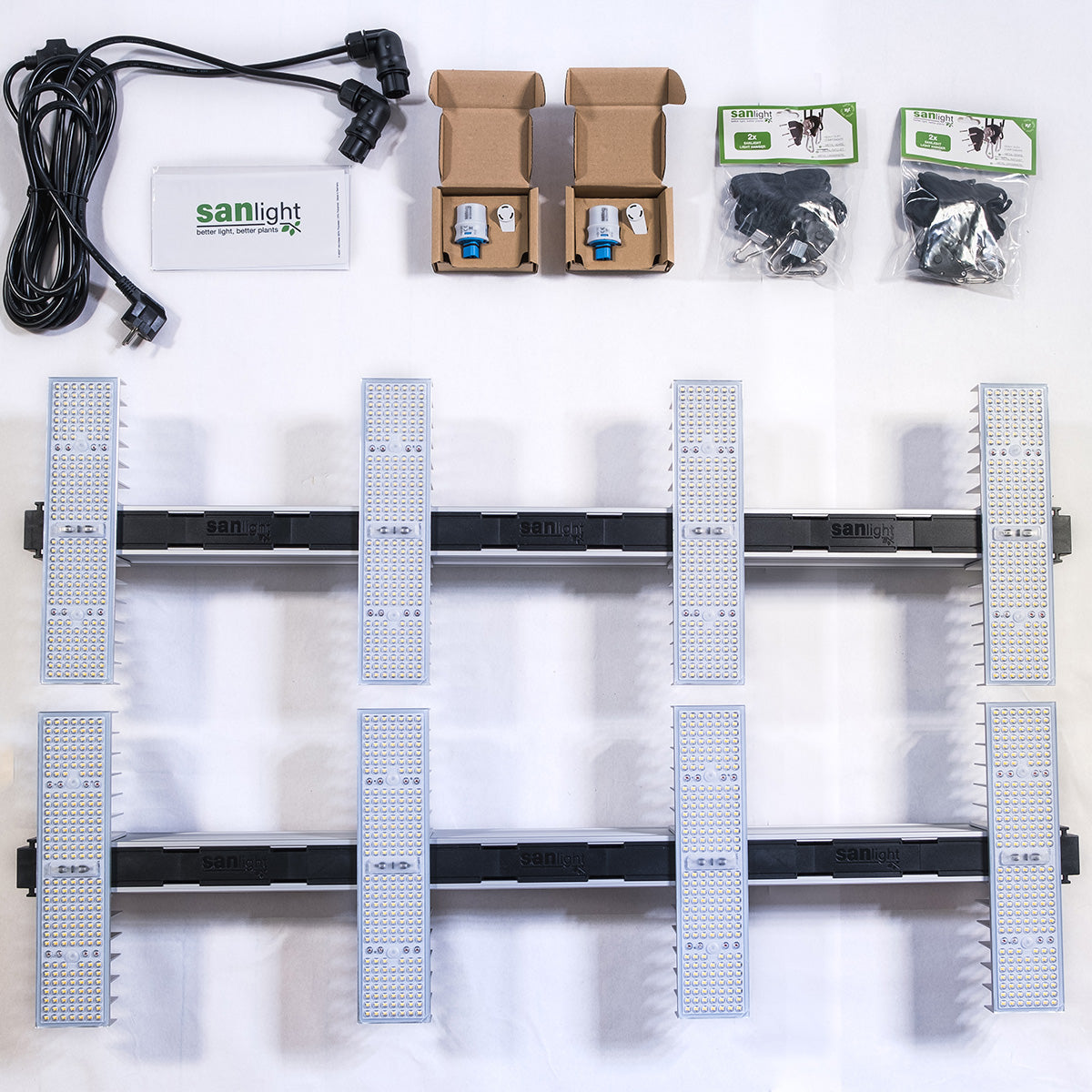 SANlight EVO 4-120 Komplett-Set ausgepackt: Das SANlight EVO 4-120 Set besteht aus mehreren LED-Panels, Stromkabeln, Montagematerialien wie zwei manuellen Dimmern und Aufhängesets sowie einem Benutzerhandbuch. Die Komponenten sind übersichtlich angeordnet.